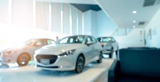 Blurred front view of white car and customer. New luxury car par